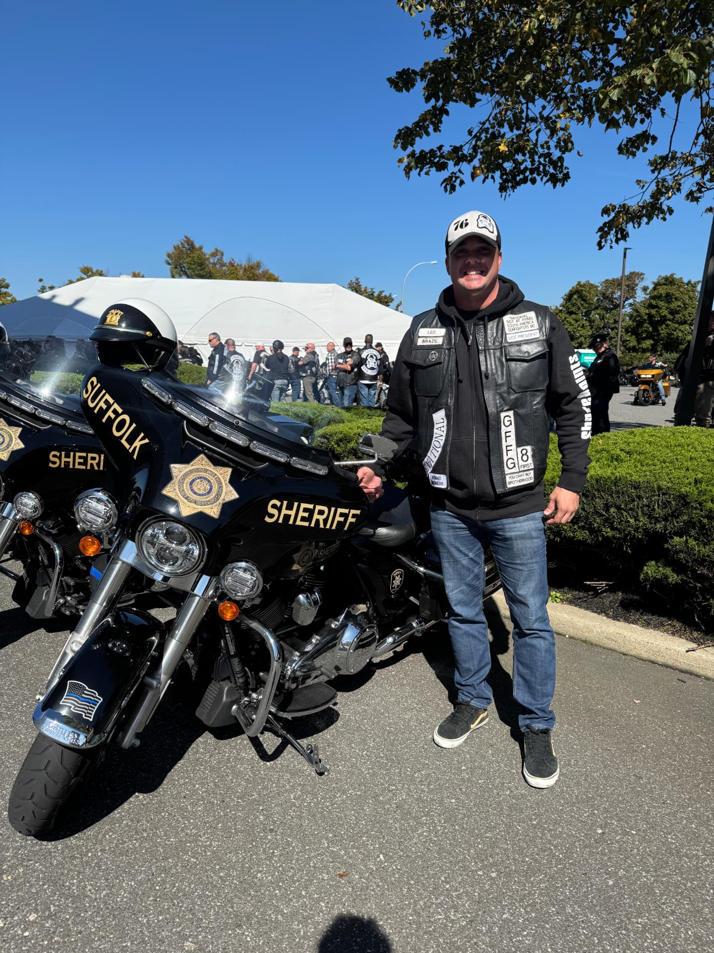 Integrante da Chapter Brazil ao lado de motocicleta do Suffolk Sheriff